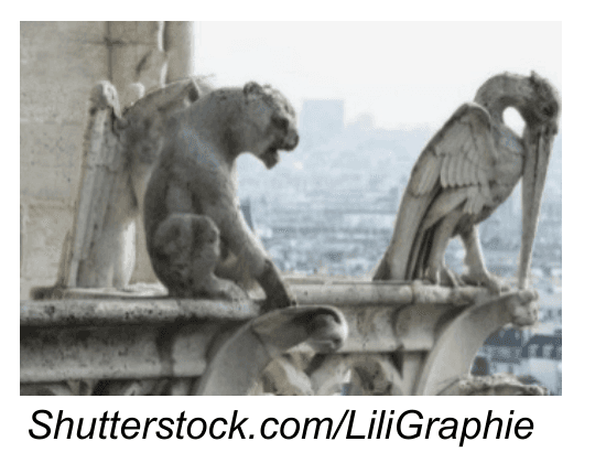 Photographie de deux statues de pierre en forme d'animaux fantastiques, posées sur une balustrade en hauteur, dominant une ville en arrière-plan flou.
